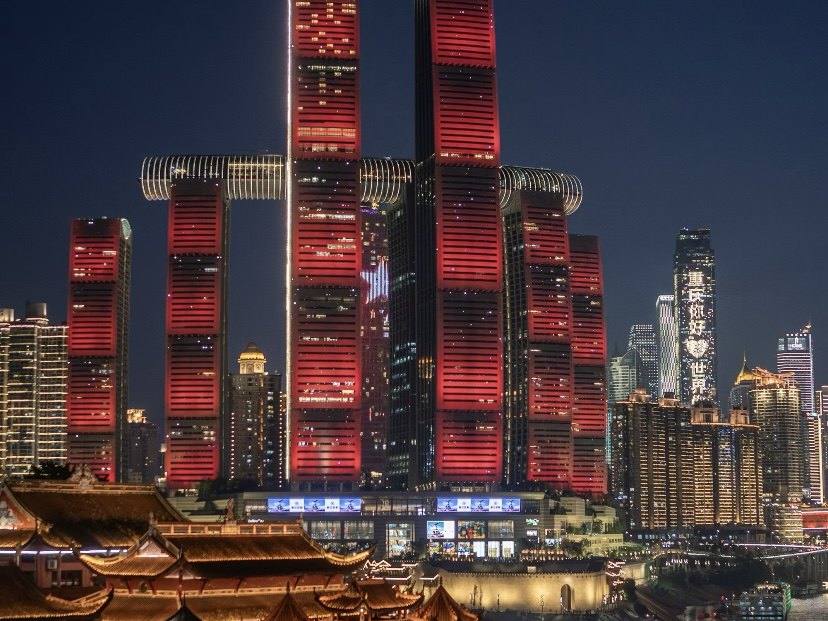 Chaotianmen towers lit red over the river at night