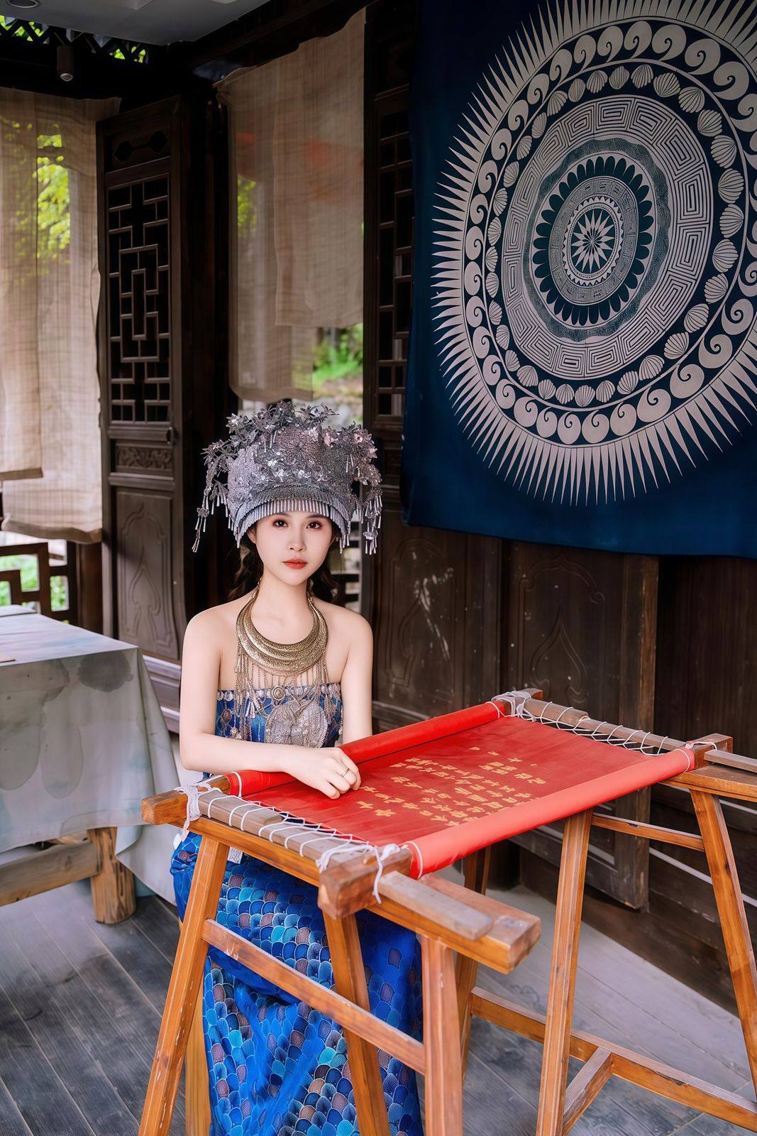 A Miao artisan at a loom beside large batik cloth at Chiyou Jiuli City